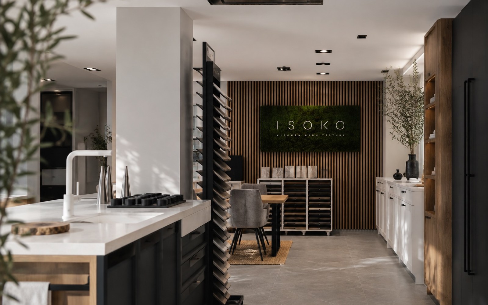 Interior del estudio ISOKO en Madrid: isla con encimera clara, muestrarios de materiales y rótulo ISOKO sobre pared de listones de madera