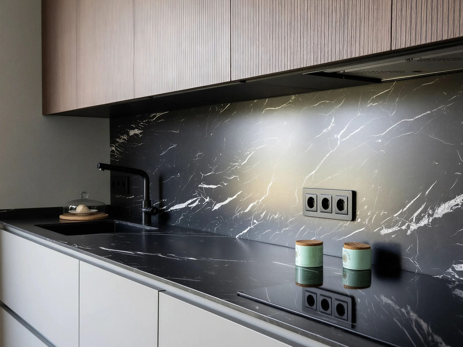 Luz rasante bajo el mueble alto lavando la veta de la piedra oscura sobre la encimera
