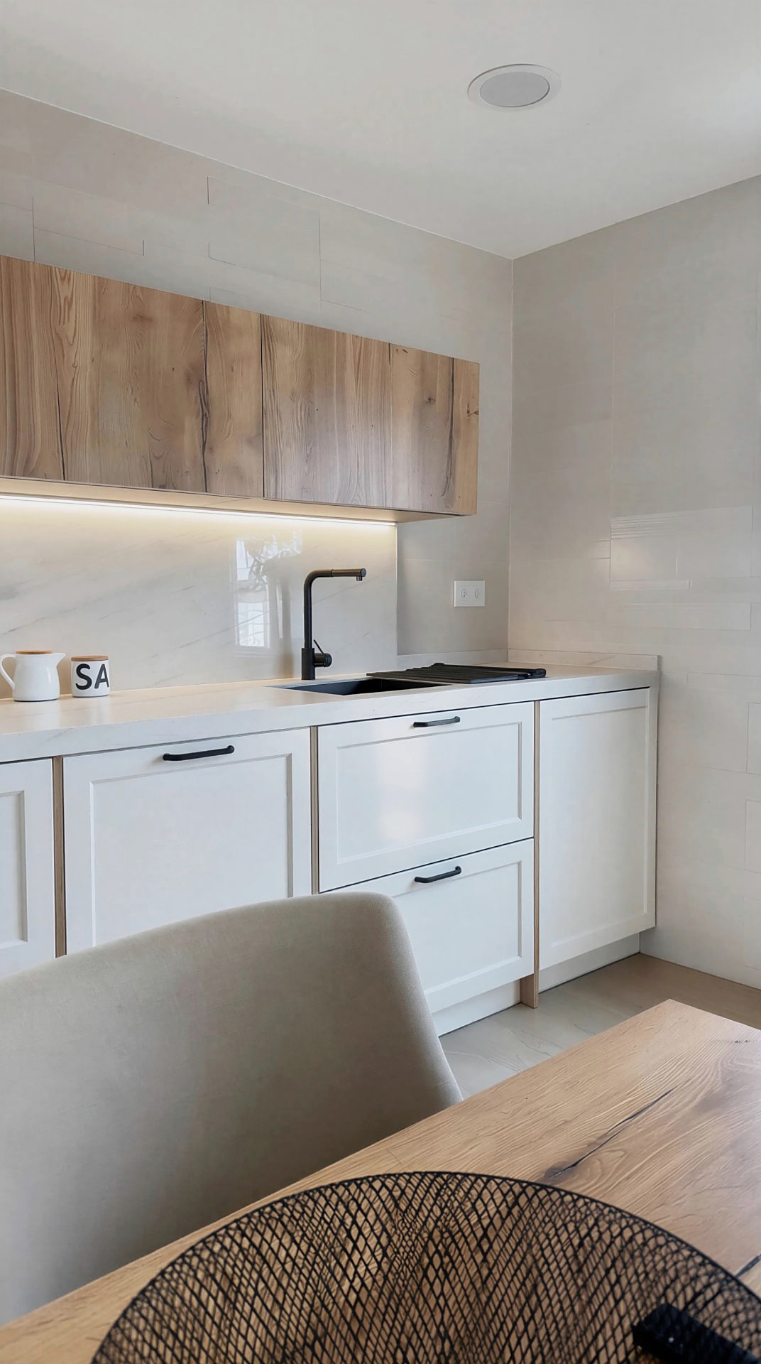 Frente de trabajo con módulo alto de madera, luz lineal y mesa de comedor en primer término