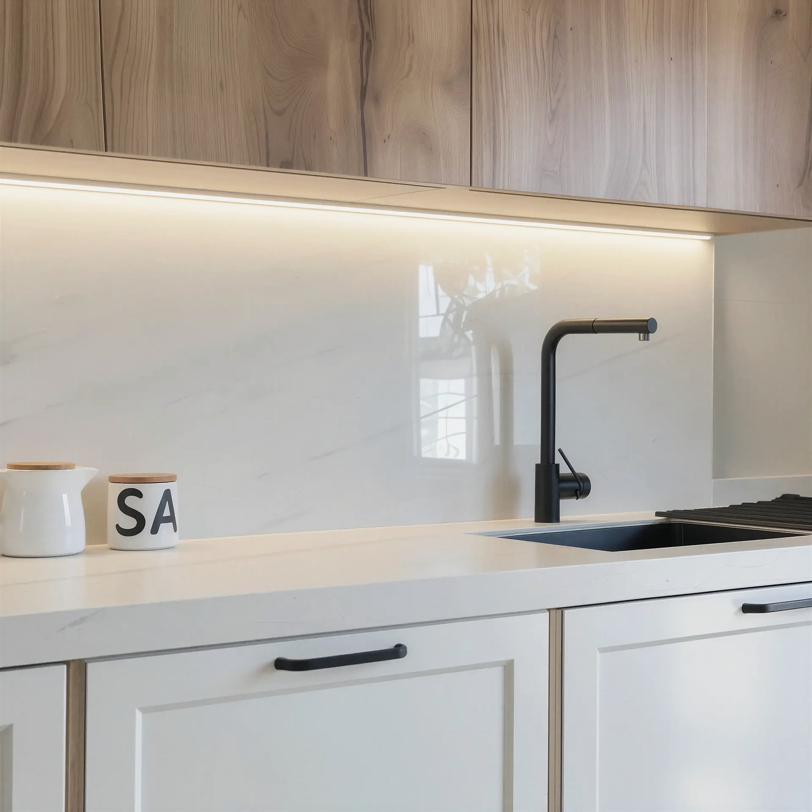 Línea de luz cálida bajo los muebles altos, lavando el frente y la encimera