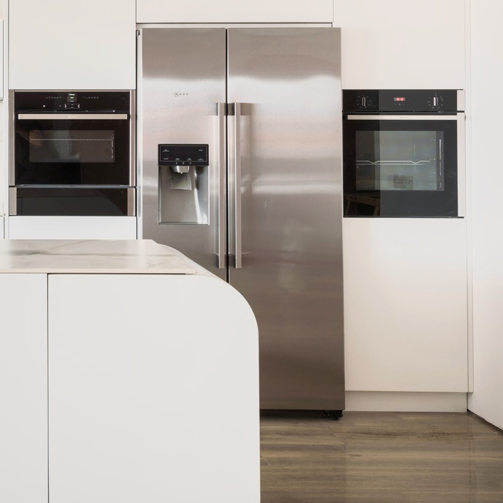 Columna de acero inoxidable y hornos de frente negro integrados en el mueble blanco