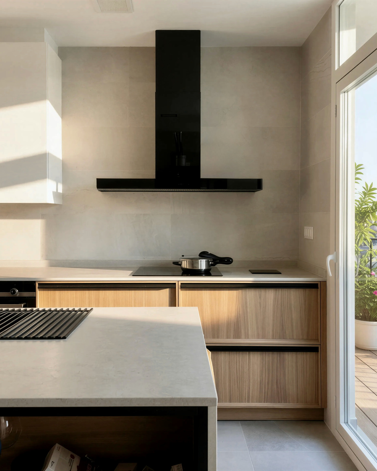 Cocina de madera clara con encimera continua, campana negra y salida a la terraza