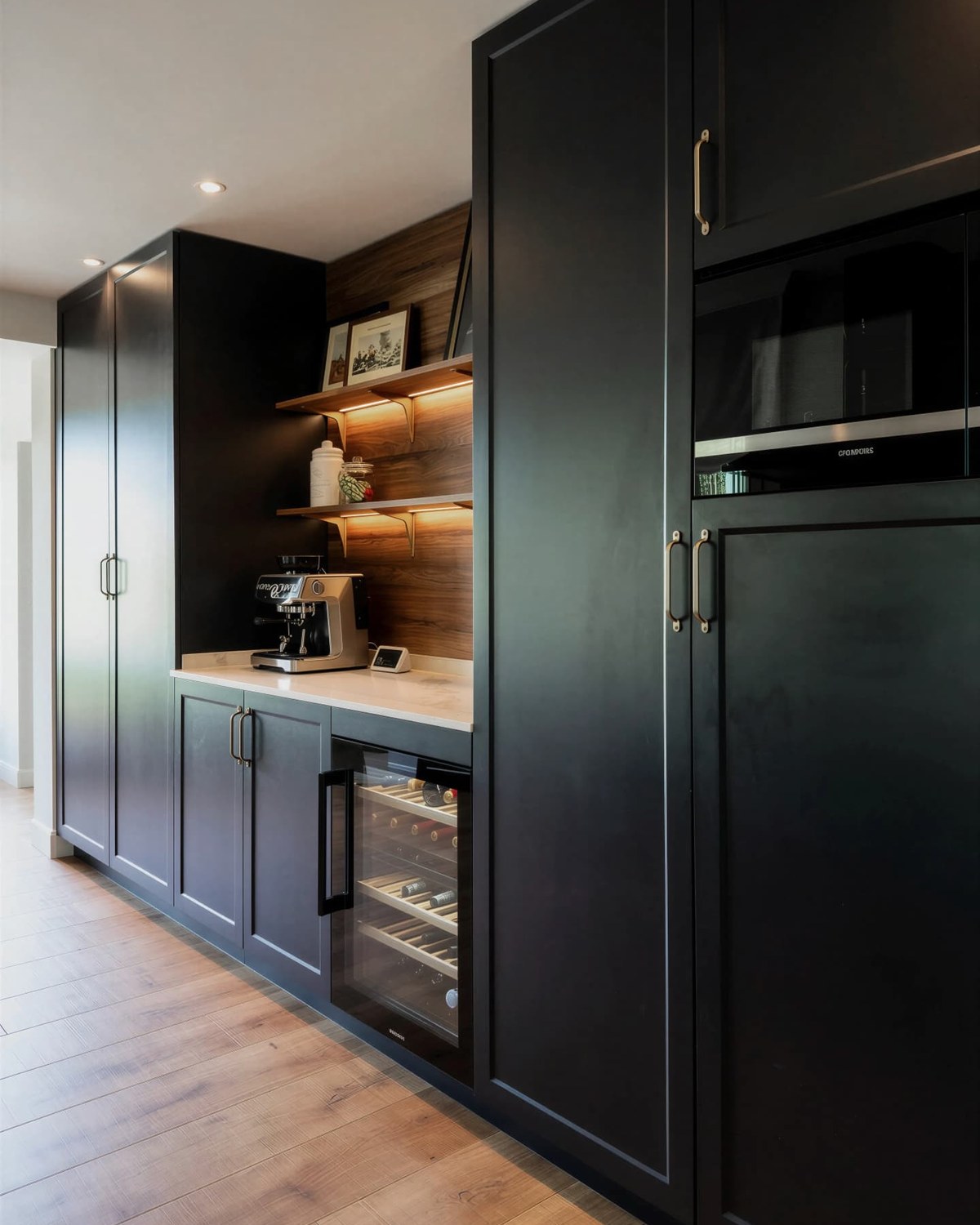 Columna oscura con hornacina de madera iluminada, cafetera y vinoteca integrada
