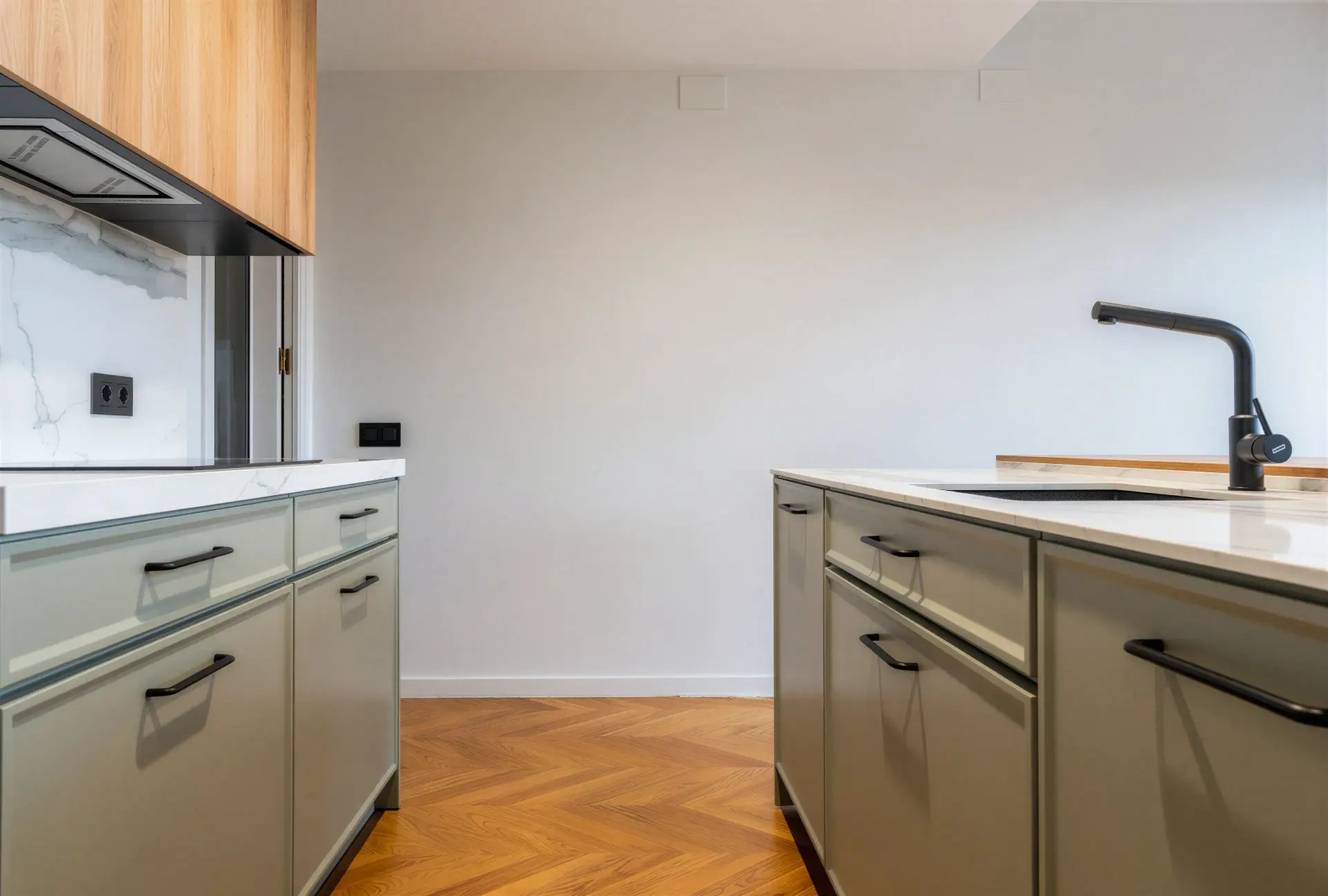 Paso entre los dos frentes de la cocina, con el suelo de espiga y el fregadero enrasado a la derecha