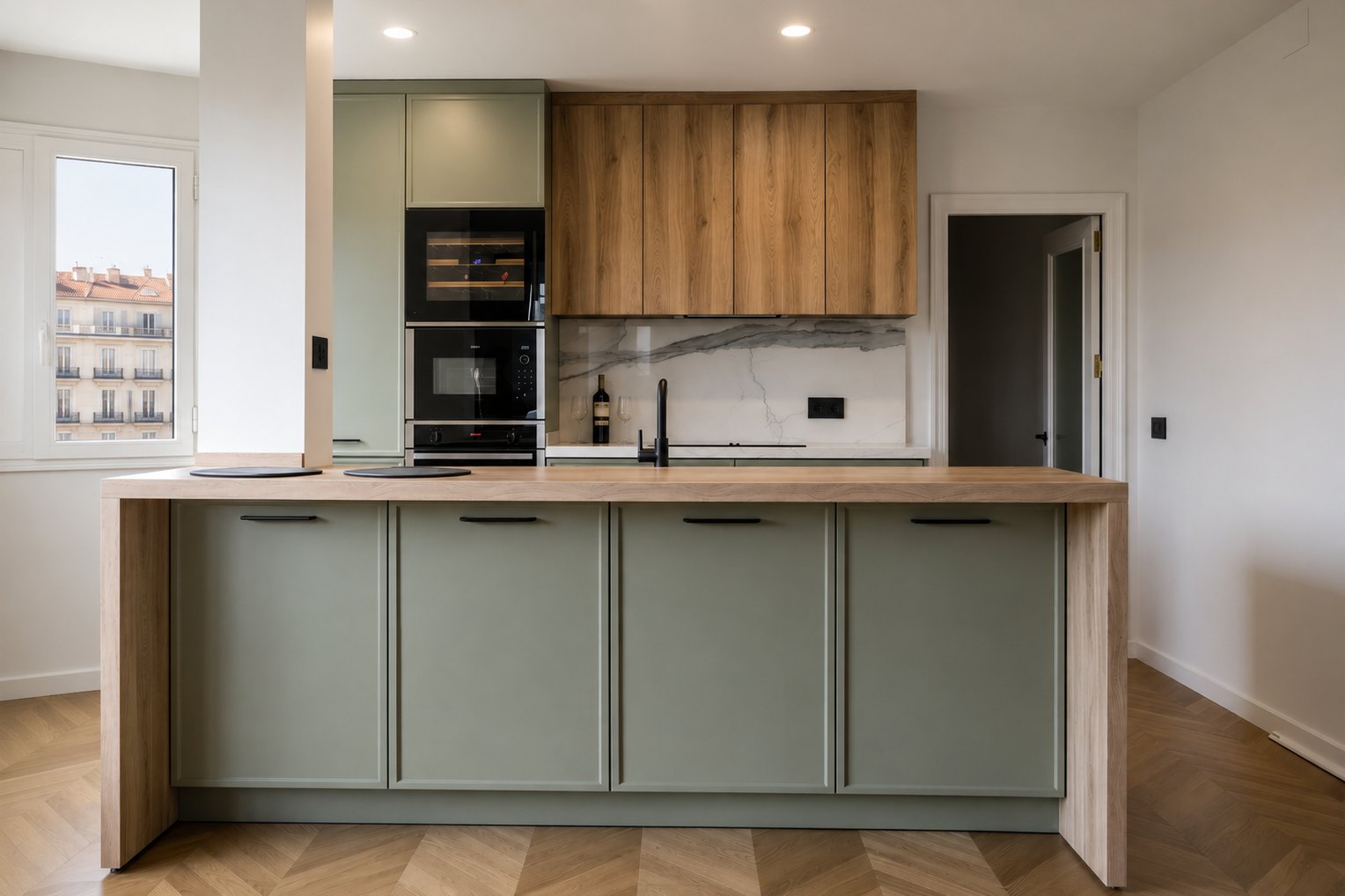 Cocina abierta con isla de madera, frentes verde hoja, altos de roble y ventana al exterior