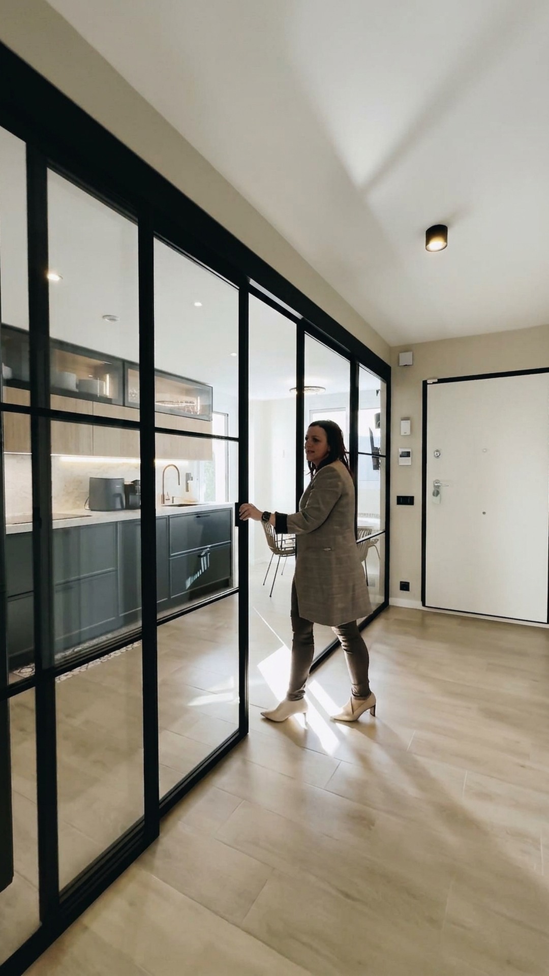 Puerta corredera de vidrio con perfilería negra abriéndose hacia la cocina, fotograma del vídeo del proyecto